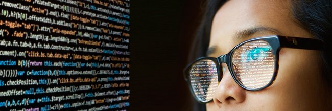 Frau mit Brille vor einem Zahlencode am Bildschirm