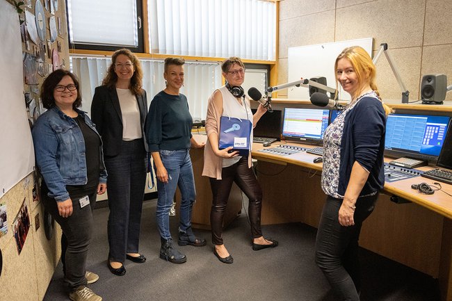 Fünf Frauen stehen im Radio Studio, sie lachen