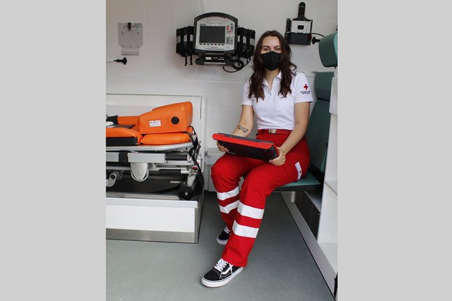 Die junge Studierende Anna Reisner sitzt im Rettungswagen, sie trägt die Uniform des Österreichischen Roten Kreuzes und eine schwarze FFP2 Maske