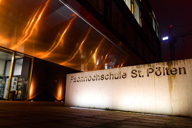 Das orange beleuchtete Gebäude A des Campus St. Pölten für die Aktion "Gegen Gewalt an Frauen"