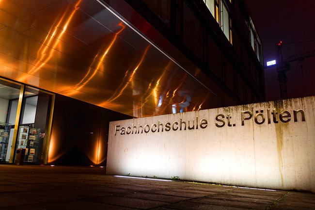 The orange illuminated building A of the St. Pölten campus for the campaign "Against violence against women"